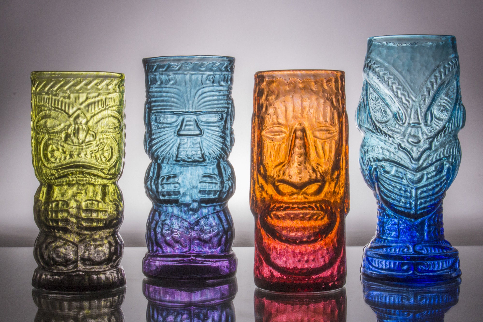 left to right: O.G. Tiki Mug in jungle fog, Warrior Tiki Mug in Eclipse, Moai Tiki Mug in lava red, and Headhunter Tiki Mug in Blue Lagoon