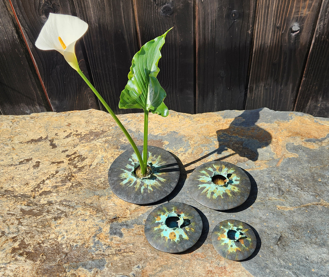 The four smallest sizes of Lens vases in tricolor patina, with lily.