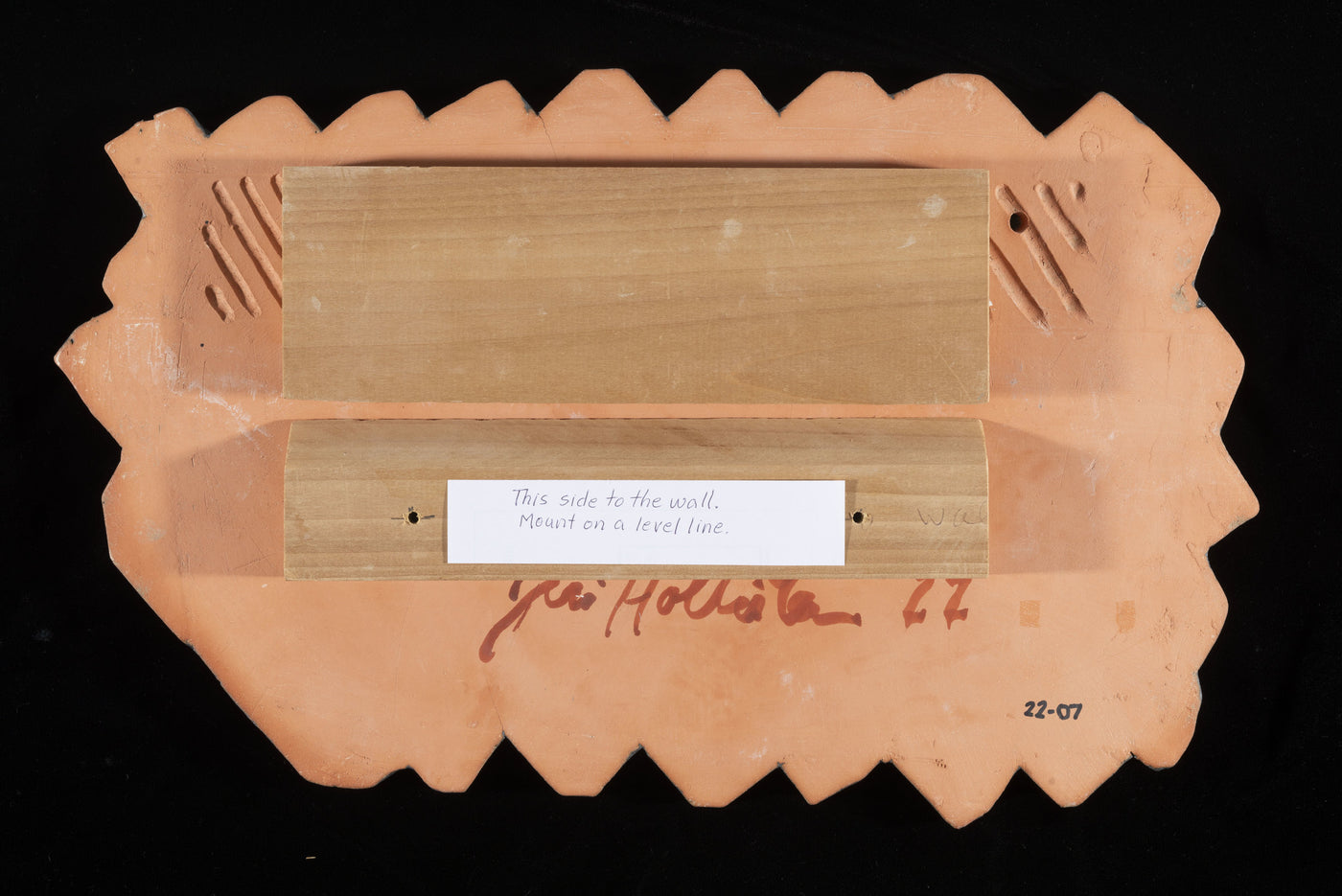 Back of tile with mounting board. Top board is mounted to tile with construction adhesive. Bottom board is to be mounted on the wall. Top board locks into bottom board when on the wall.