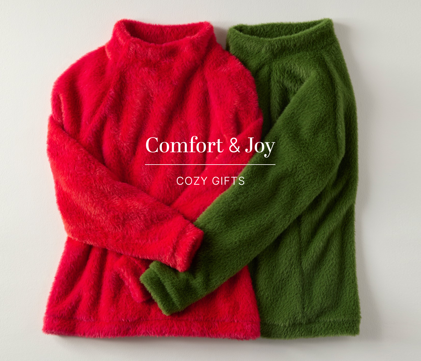 Comfort & Joy: Shop Cozy Gifts text with an image of red and green fuzzy sweaters