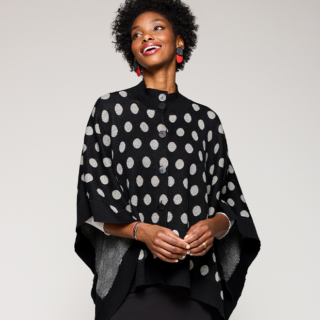 Woman wearing a black polka dot poncho. Shop Olea Cape.