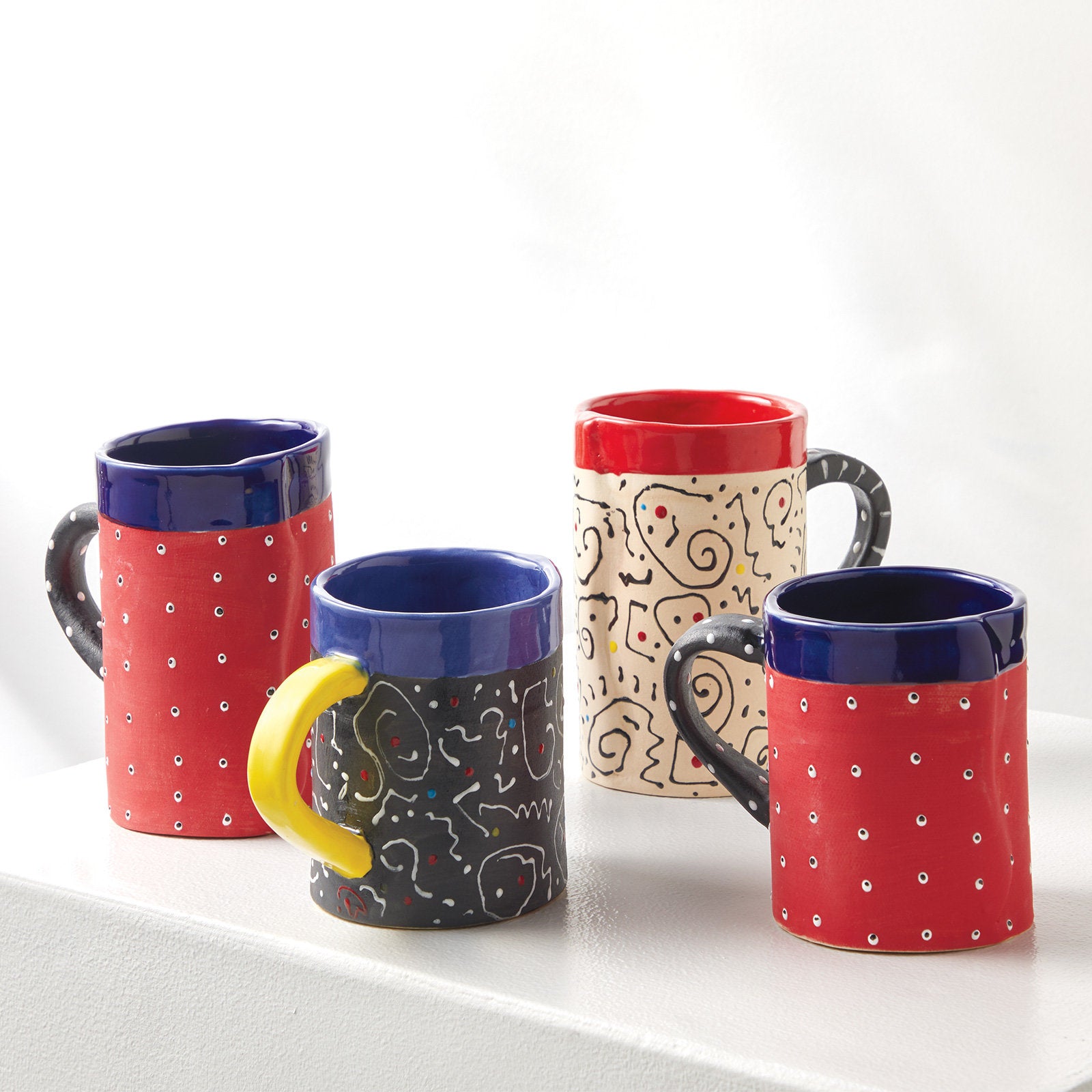 left to right: tall Velvet Red Mug, short white squiggle mug, tall squiggle mug, short Velvet Red Mug