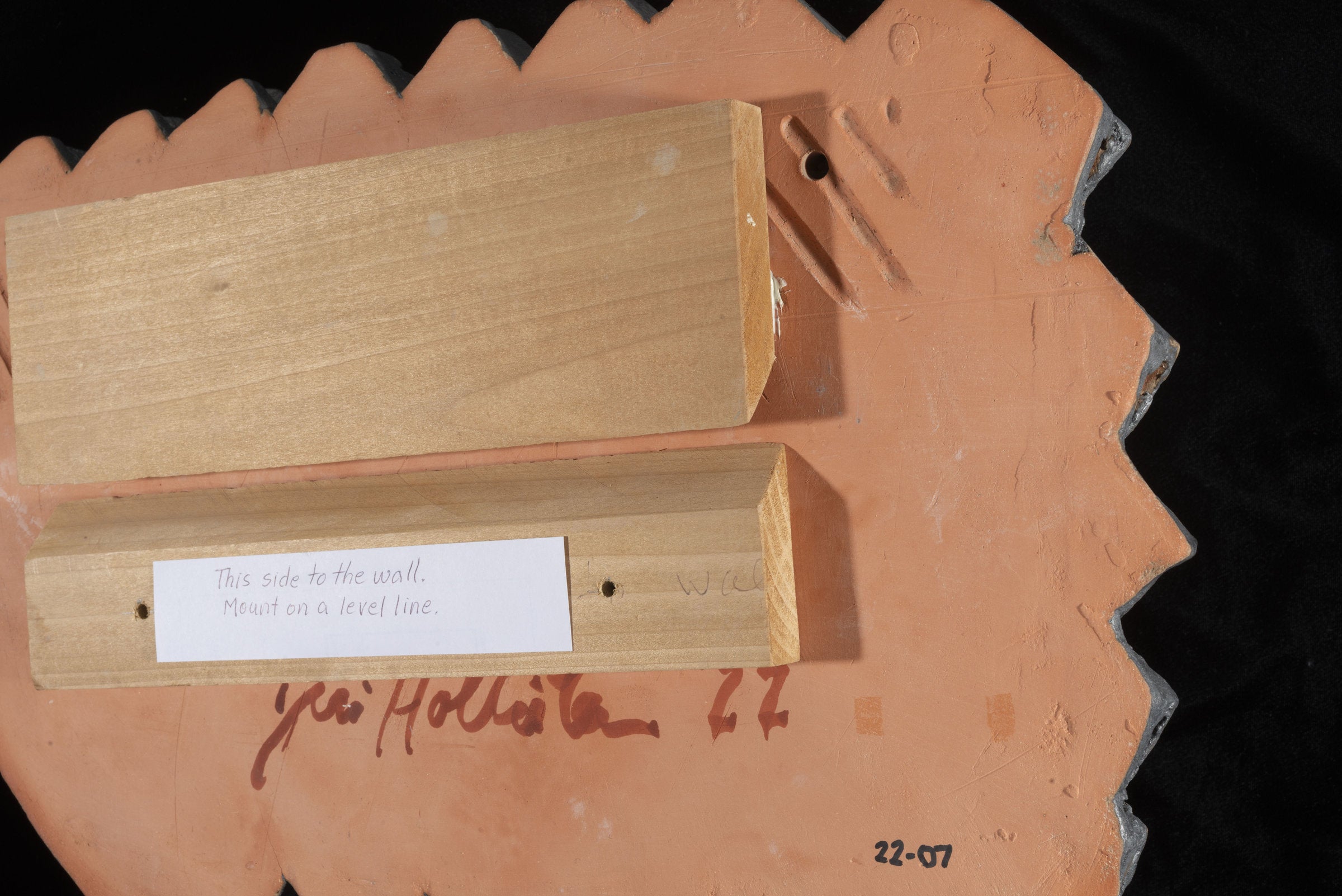 Back of tile with mounting board. Top board is mounted to tile with construction adhesive. Bottom board is to be mounted on the wall. Top board locks into bottom board when on the wall.