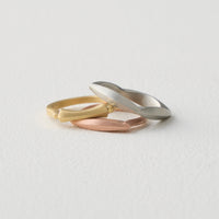 stacked top to bottom: Four Allonge Band in 18k white gold, Hourglass Stacking Ring in 18k yellow gold, Allonge Stacking Ring in 18k rose gold