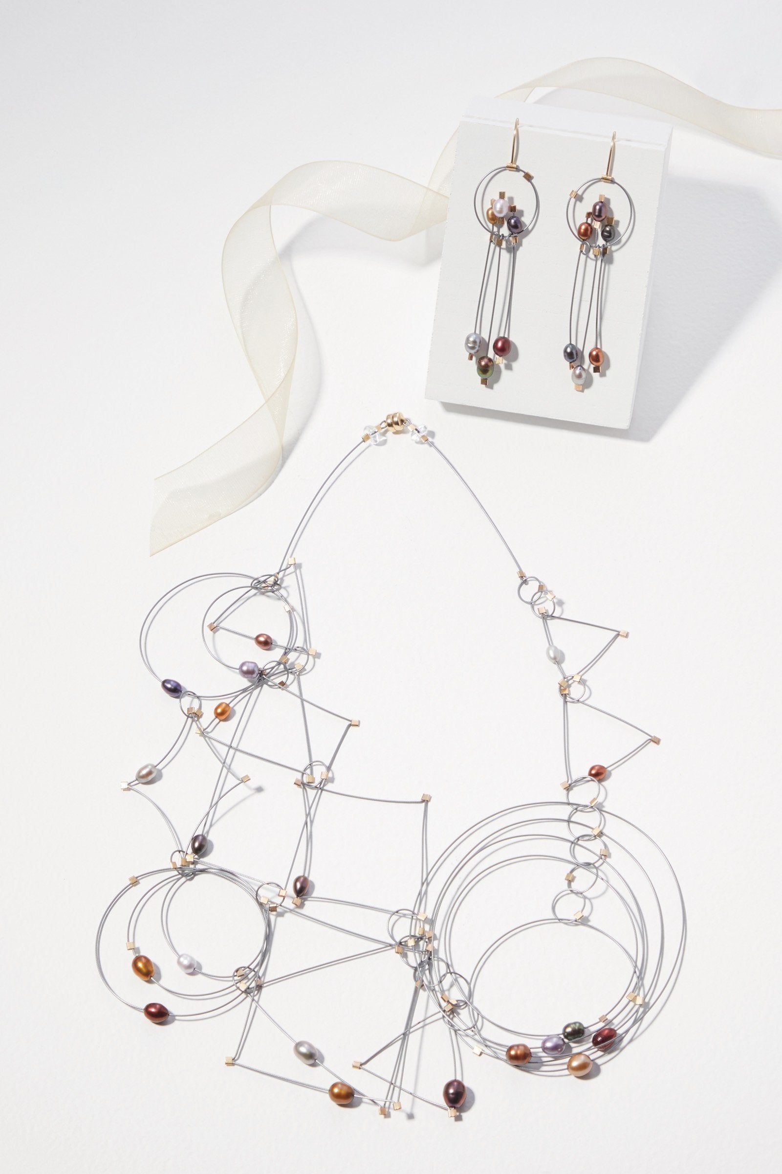 shown with the artist's coordinating trapeze necklace