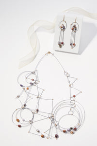 shown with the artist's coordinating trapeze necklace